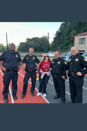 A woman posing with four men in police and sheriff's deputy uniforms.